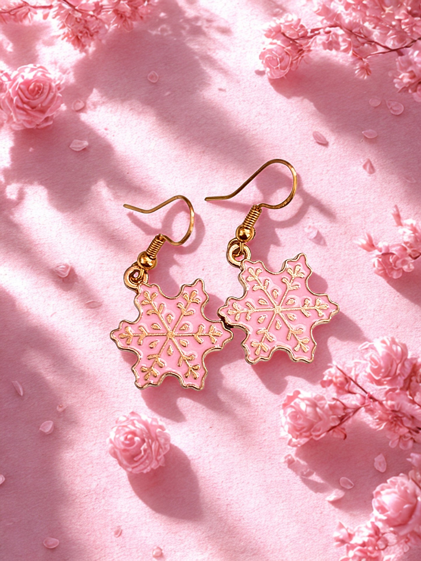 Pink snowflake earrings on a pink floral background