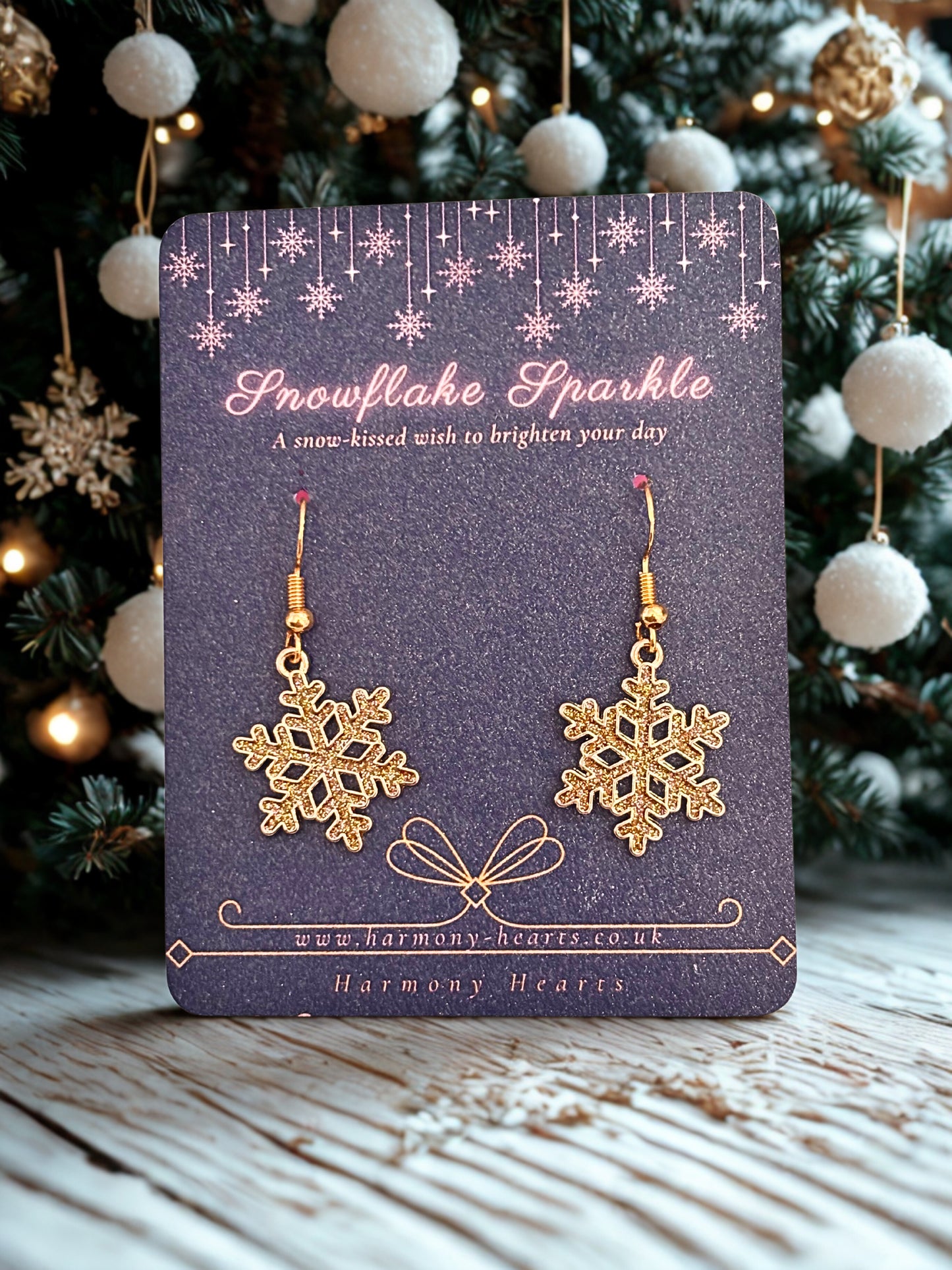 Gold snowflake earrings on a blue card with Christmas decorations in the background
