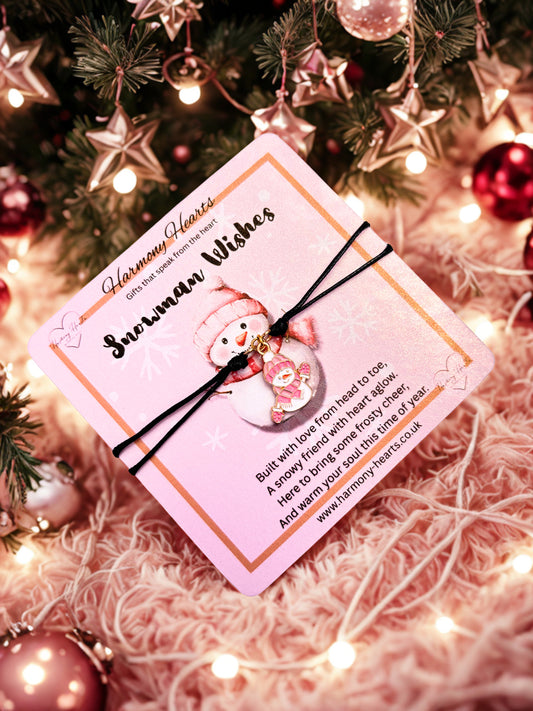 Snowman bracelet on a Snowman-themed card with pink border on a Christmas tree with lights and ornaments.