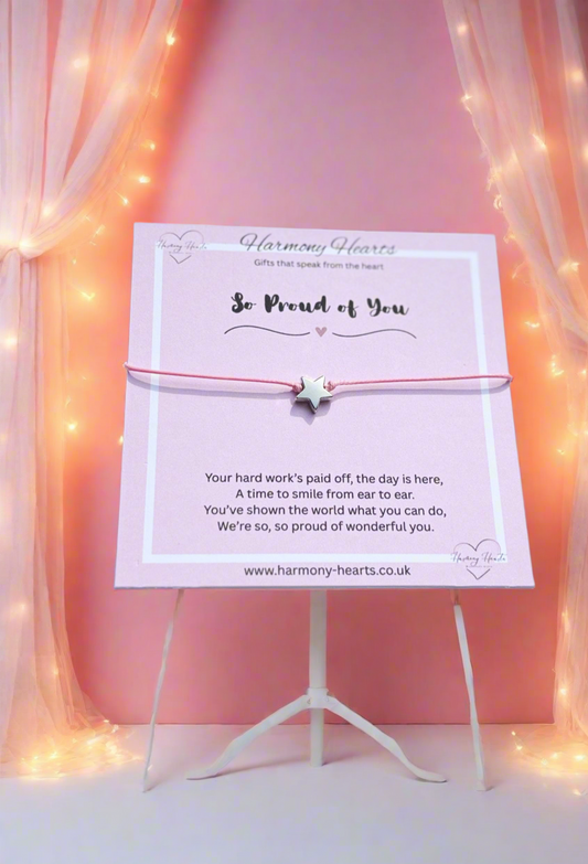 Easel with a card and bracelet against a pink background with fairy lights