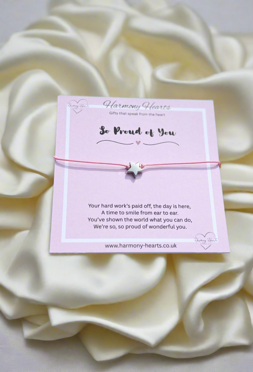 Pink card with a message and a bracelet on a white fabric background