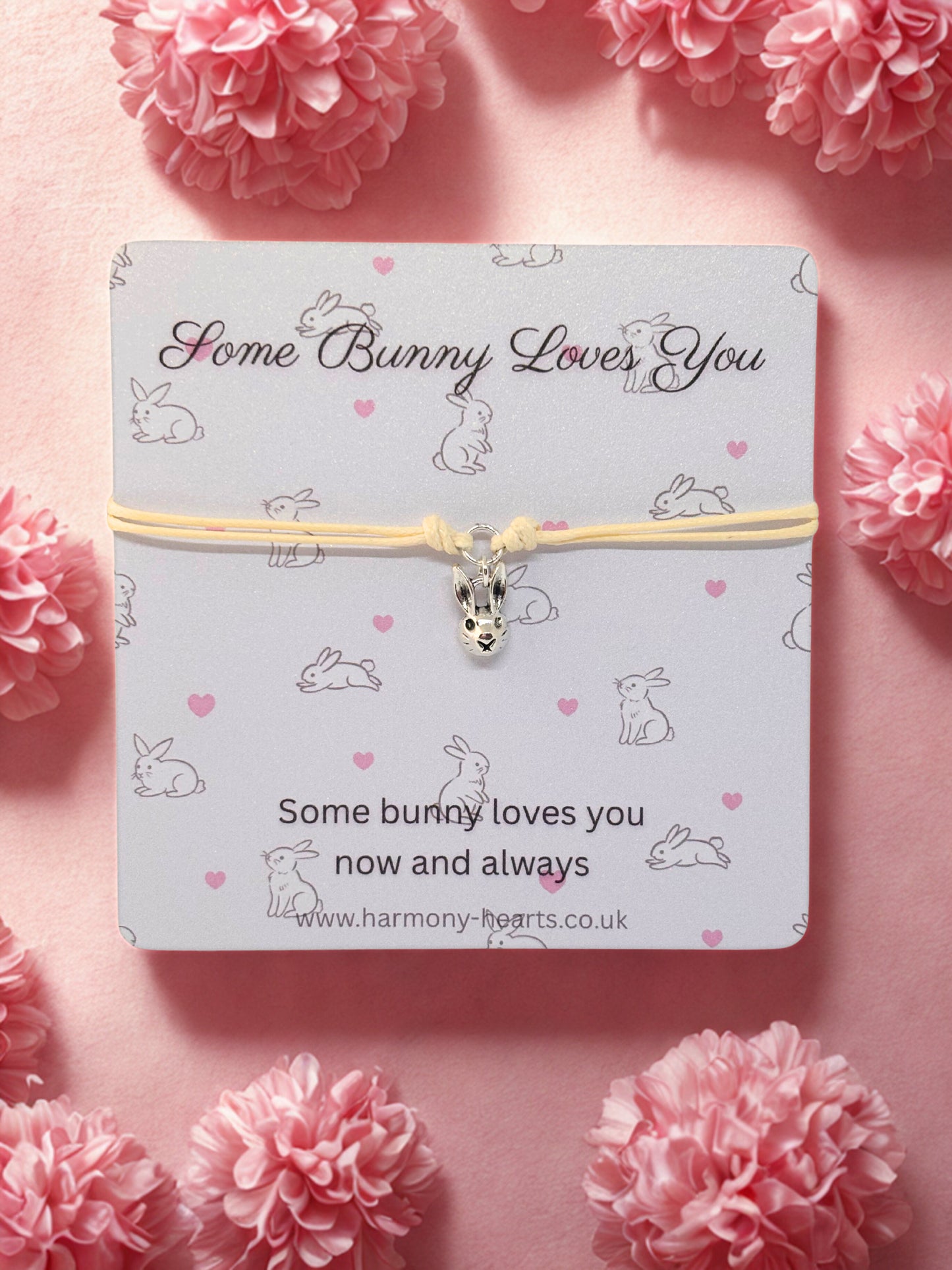 Bunny-themed bracelet on a card with pink flowers around