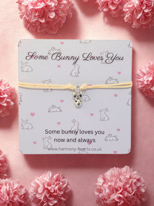 Bunny-themed bracelet on a card with pink flowers around
