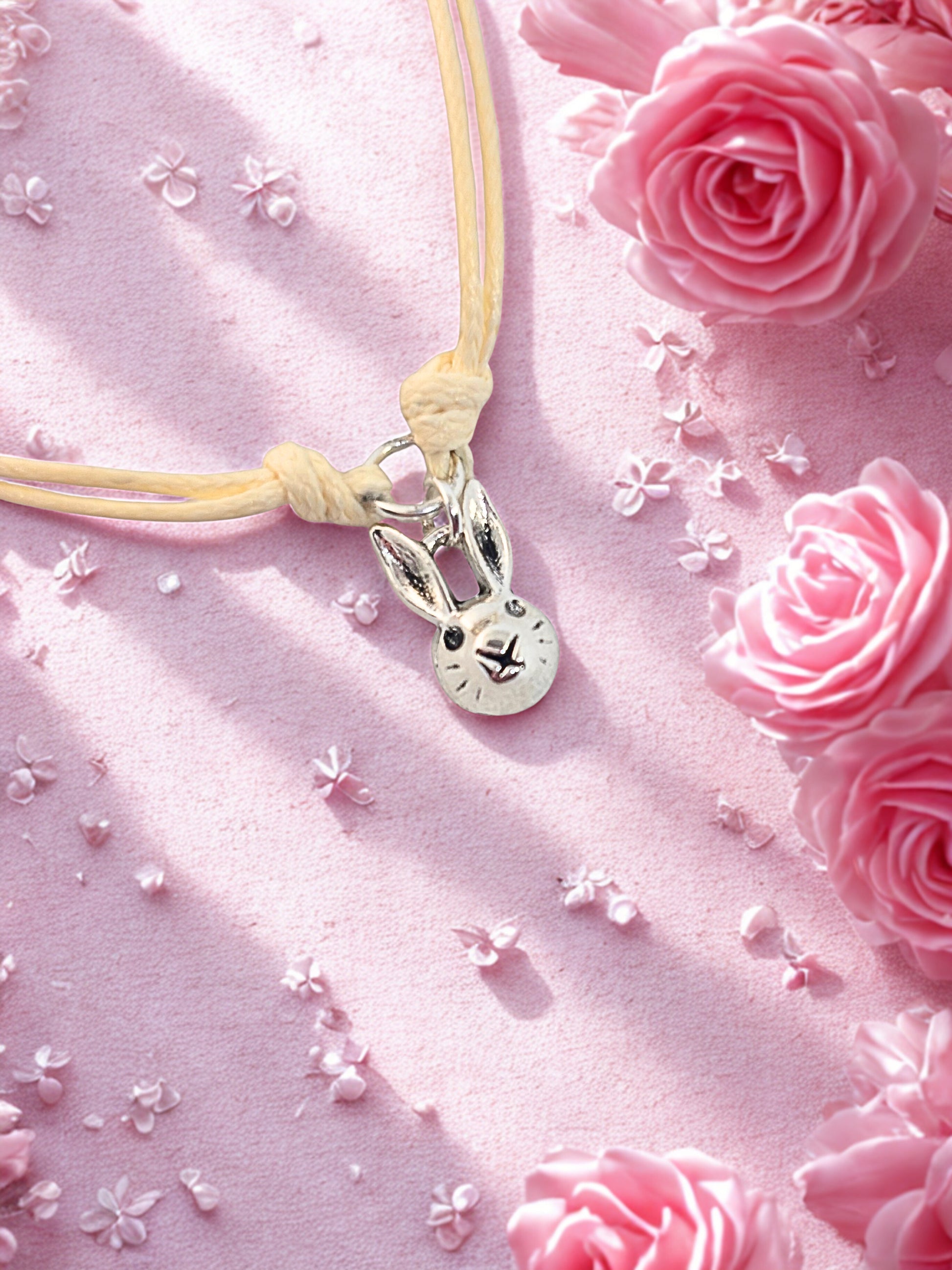 Bracelet with a bunny charm on a pink fabric background with roses