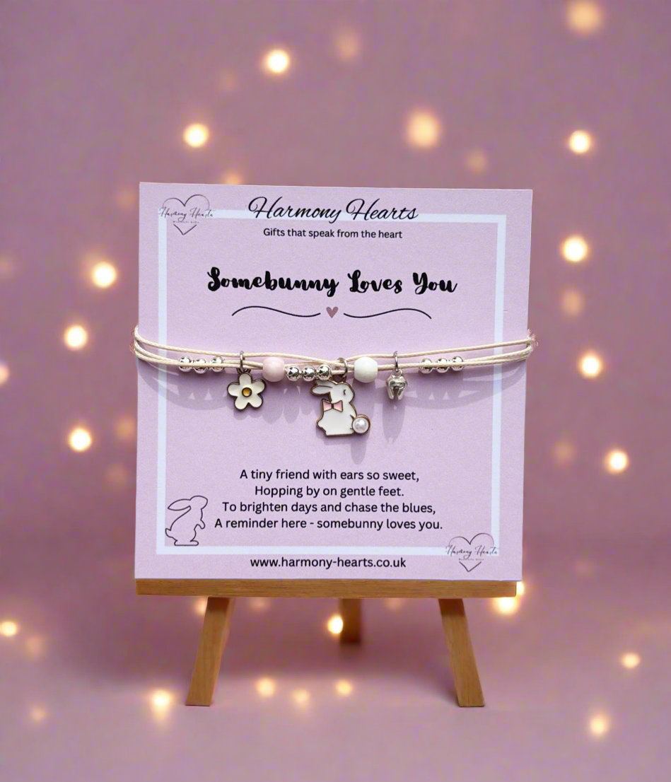 Bracelet with charms on a display card against a soft purple background with lights.