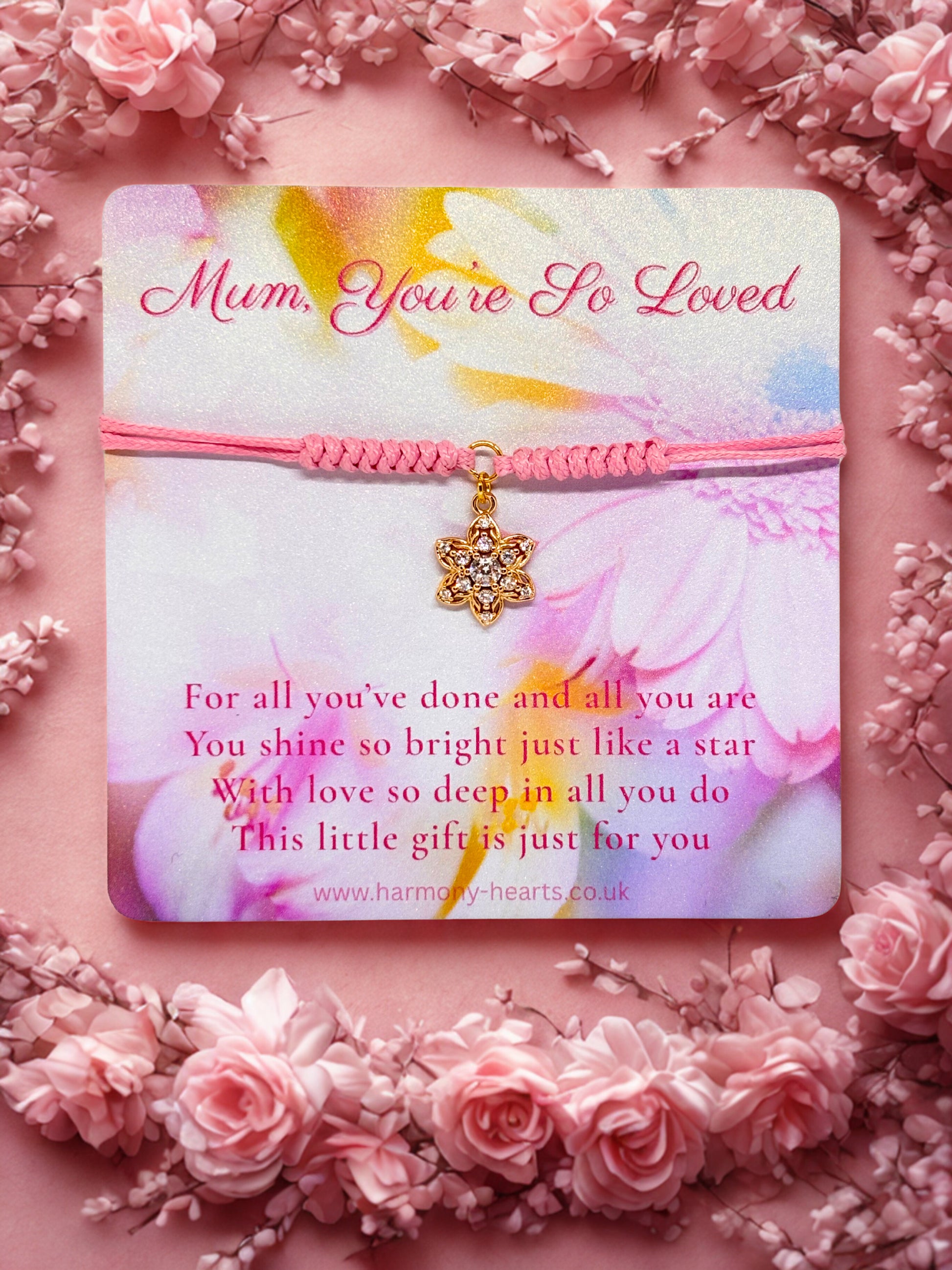 Pink cord bracelet with sparkly gold flower charm presented on a Harmony Hearts branded card on a floral background