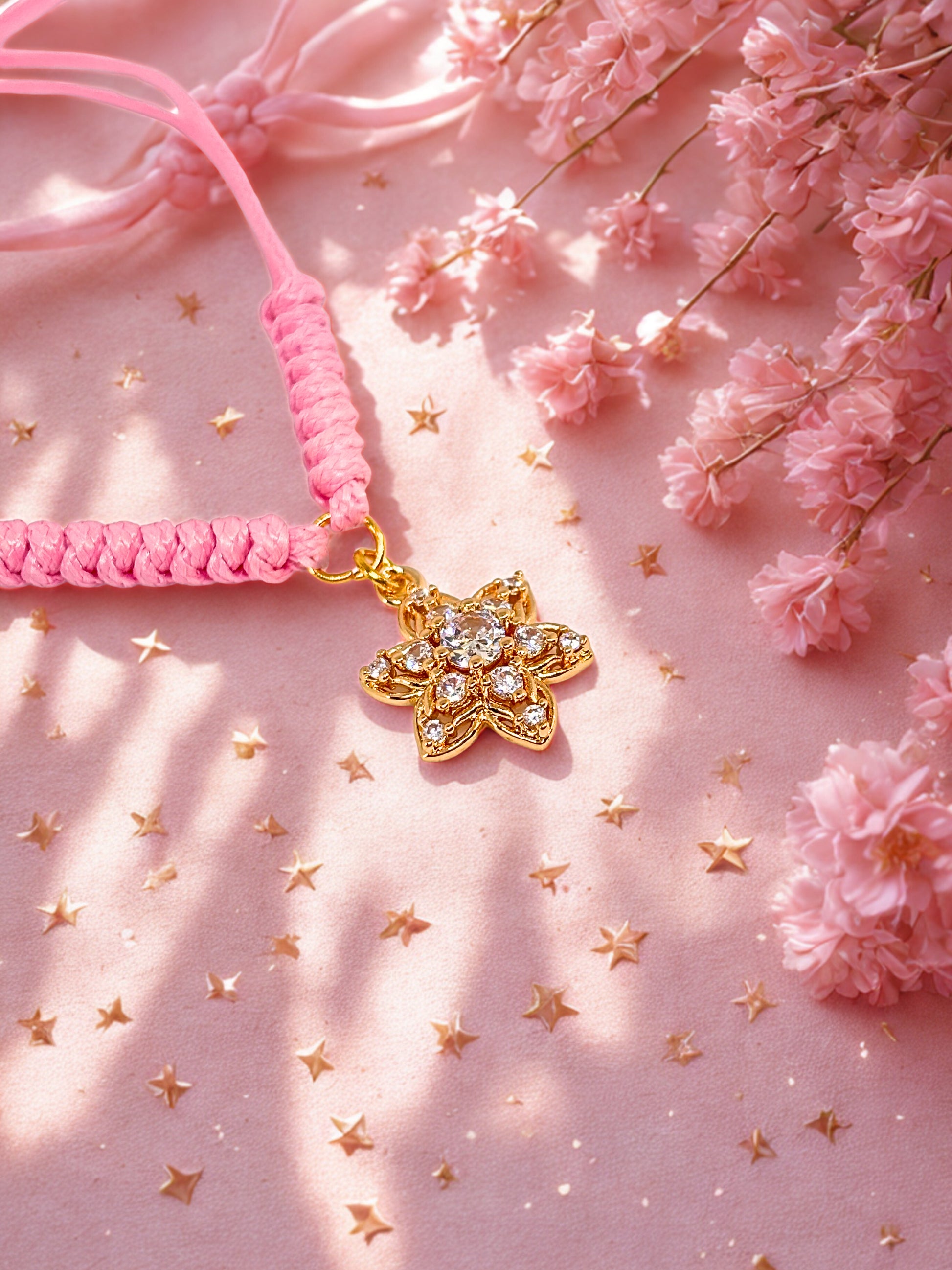 Pink bracelet with a gold flower charm on a pink background with flowers