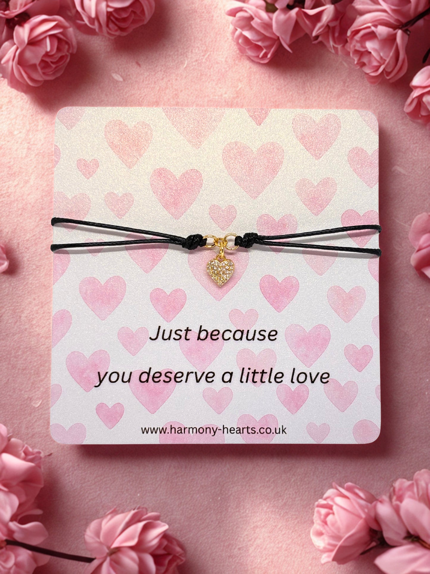 Bracelet on a card with heart pattern and text, surrounded by pink flowers