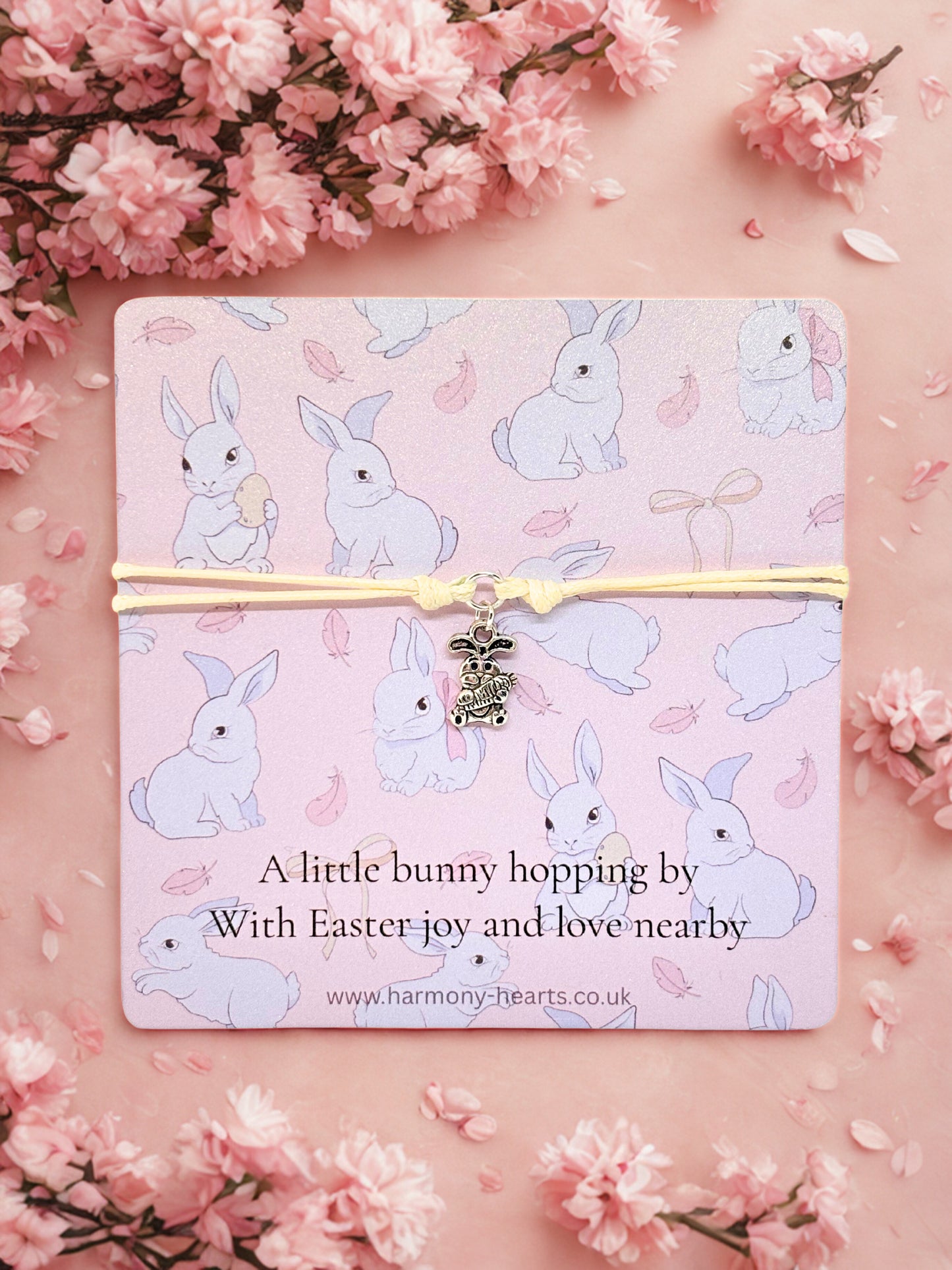 Branded Harmony Hearts card with bunny pattern and  bunny charm bracelet on a pink background