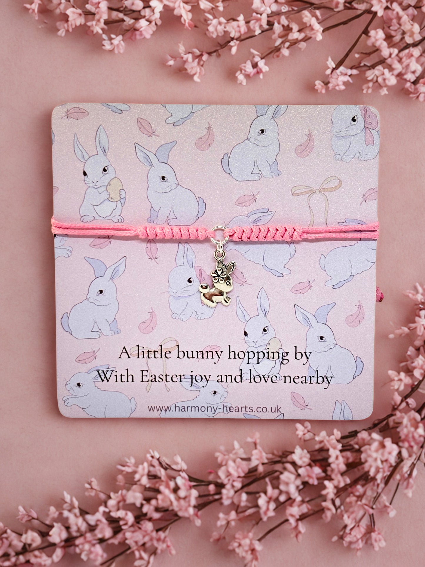 Silver and pink bunny charm bracelet presented on an Easter card with bunny pattern on a pink background with floral elements
