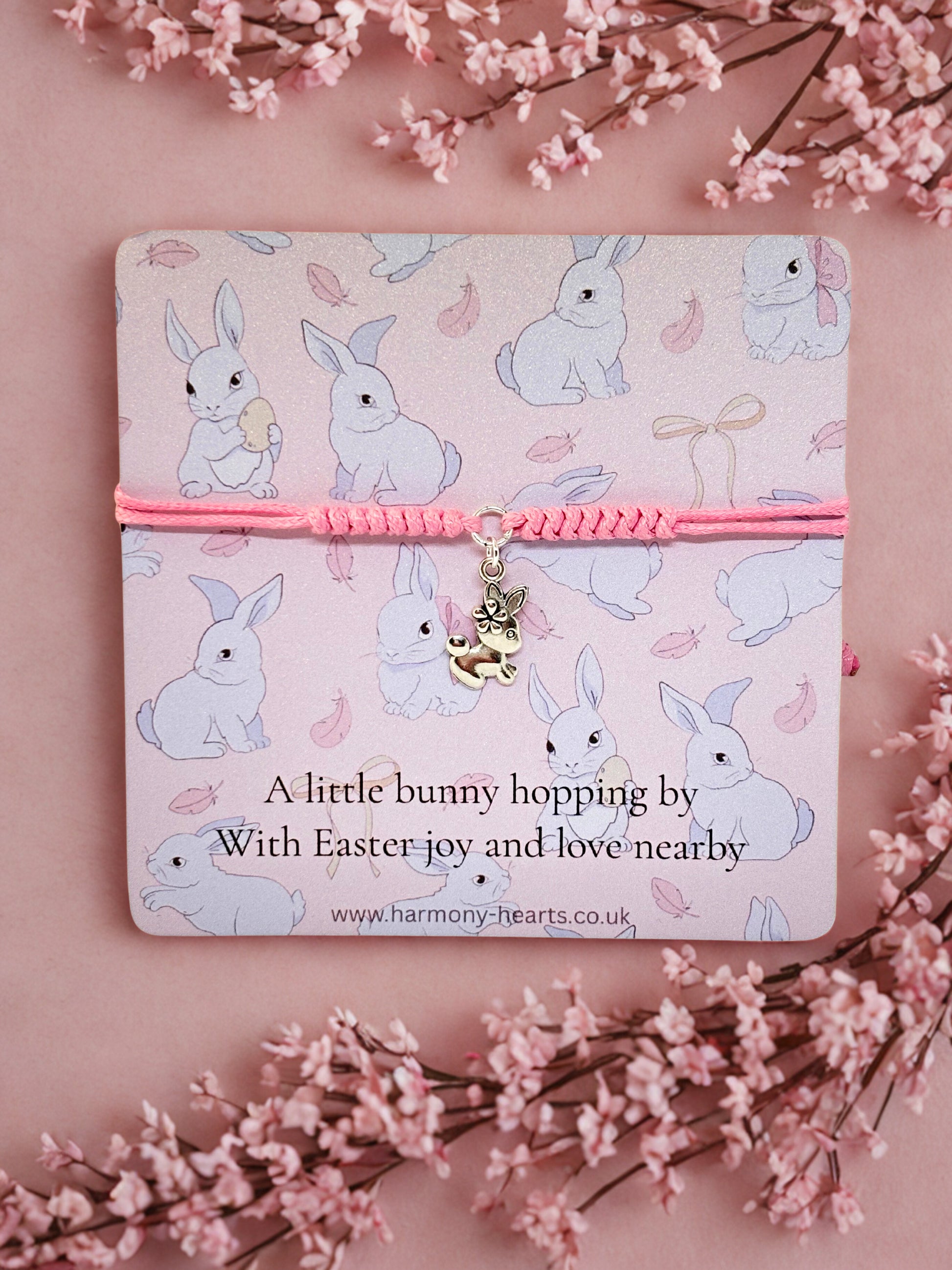 Silver and pink bunny charm bracelet presented on an Easter card with bunny pattern on a pink background with floral elements