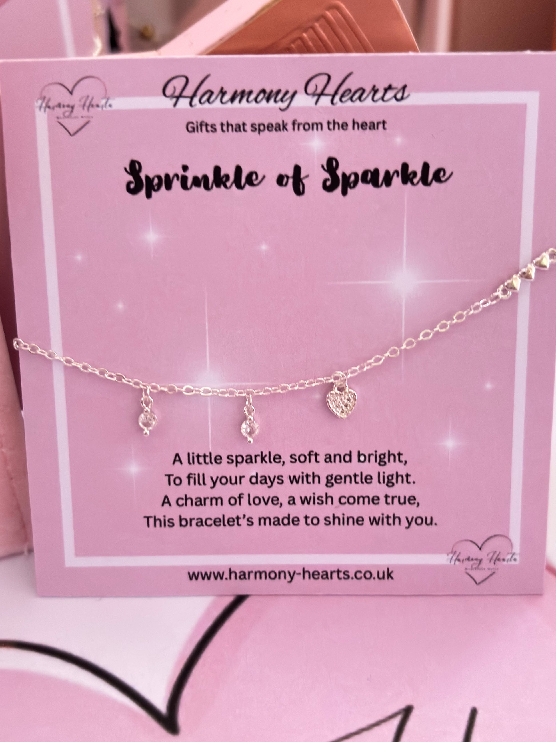 Silver tone bracelet with heart charm on a pink card with 'Harmony Hearts' branding