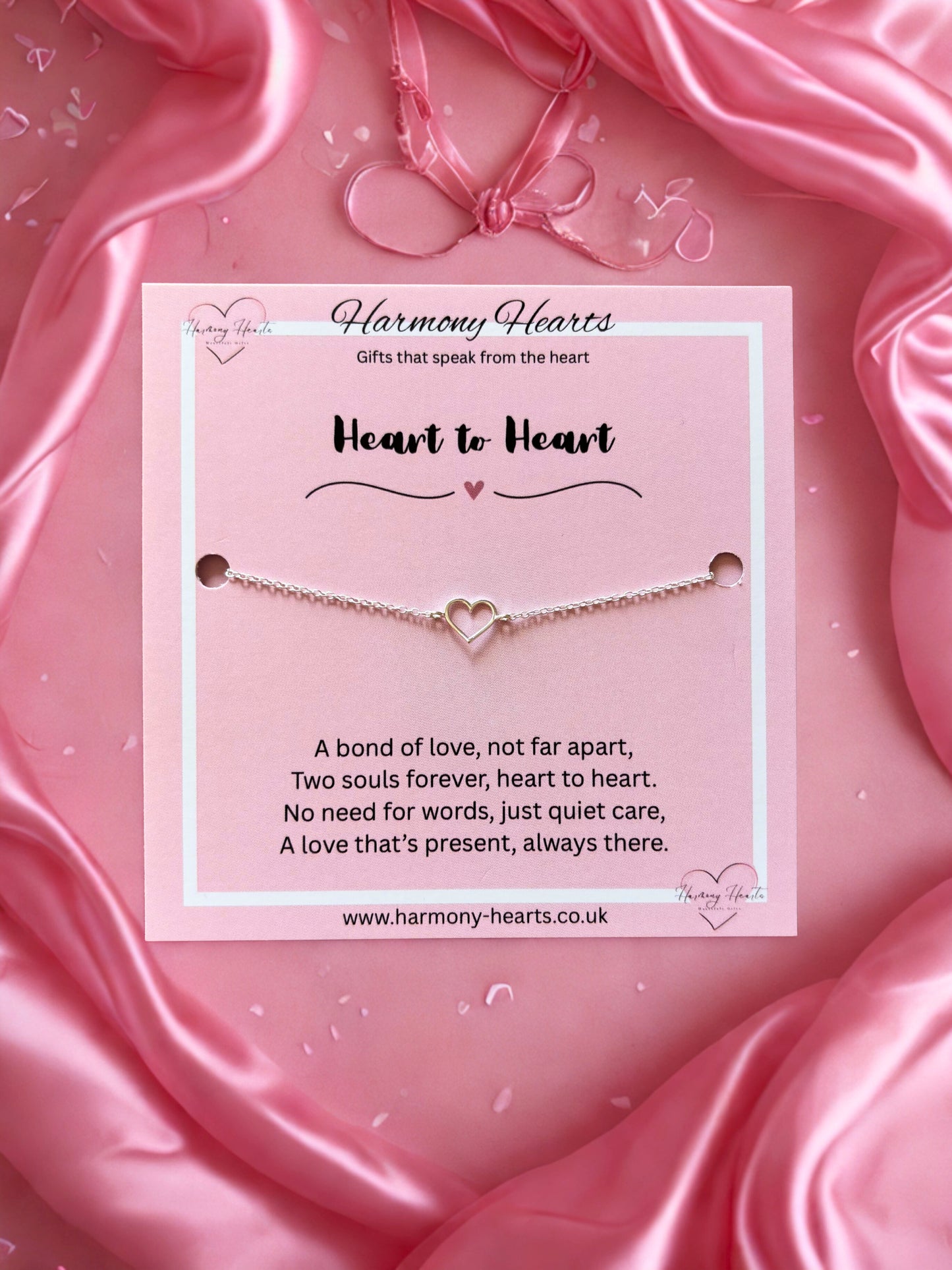 Heart-shaped bracelet on a pink satin background with 'Harmony Hearts' branding.
