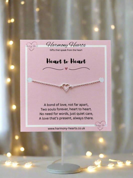 Bracelet on a stand with a pink card featuring text and 'Harmony Hearts' branding, set against a softly blurred background with lights.