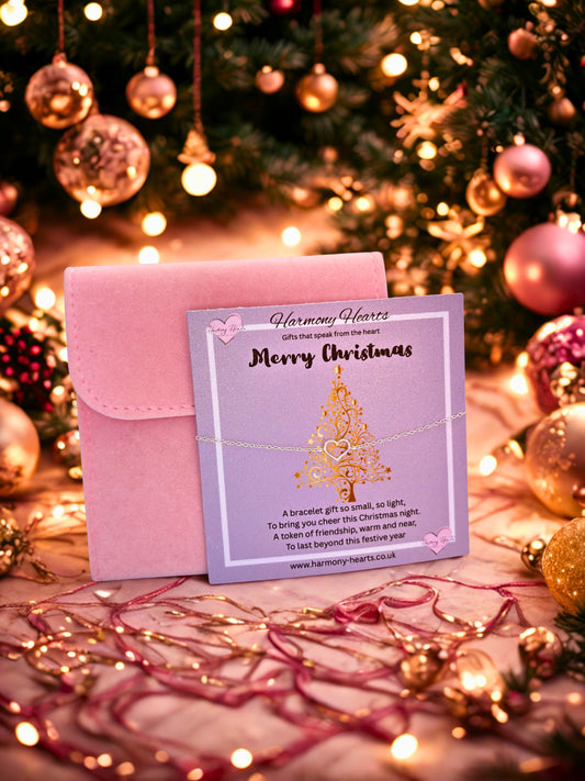 Pink card and envelope with 'Merry Christmas' message on a festive background with Christmas tree and lights.