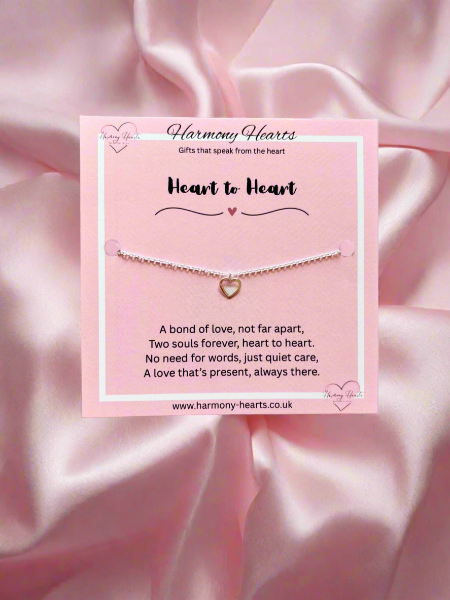 Heart bracelet on a pink card with 'Harmony Hearts' branding against a pink satin background.