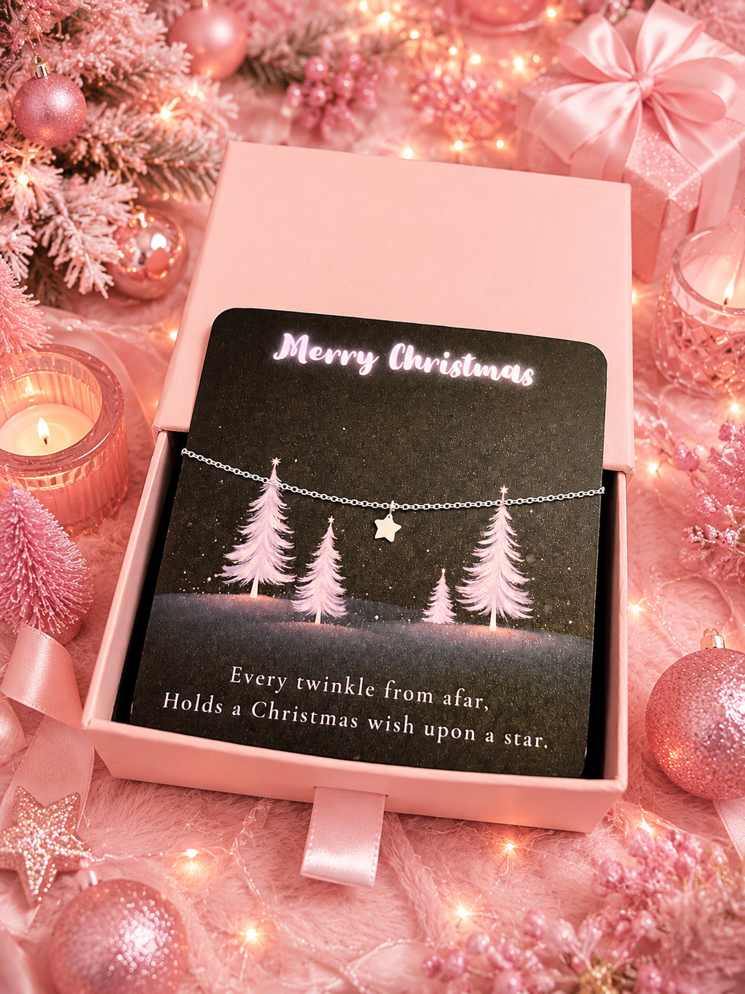 A delicate silver bracelet with a star charm is displayed on a black card inside a pink gift box. The card reads 'Merry Christmas' and 'Every twinkle from afar, Holds a Christmas wish upon a Star’