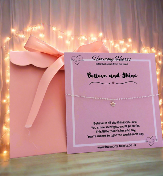 Harmony Hearts bracelet with star charm on a pink card against a soft, blurred background with lights.