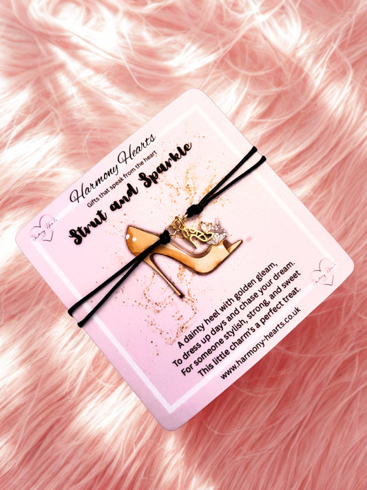 Bracelet with a gold stilletto charm on a pink card with text, against a pink fluffy background.