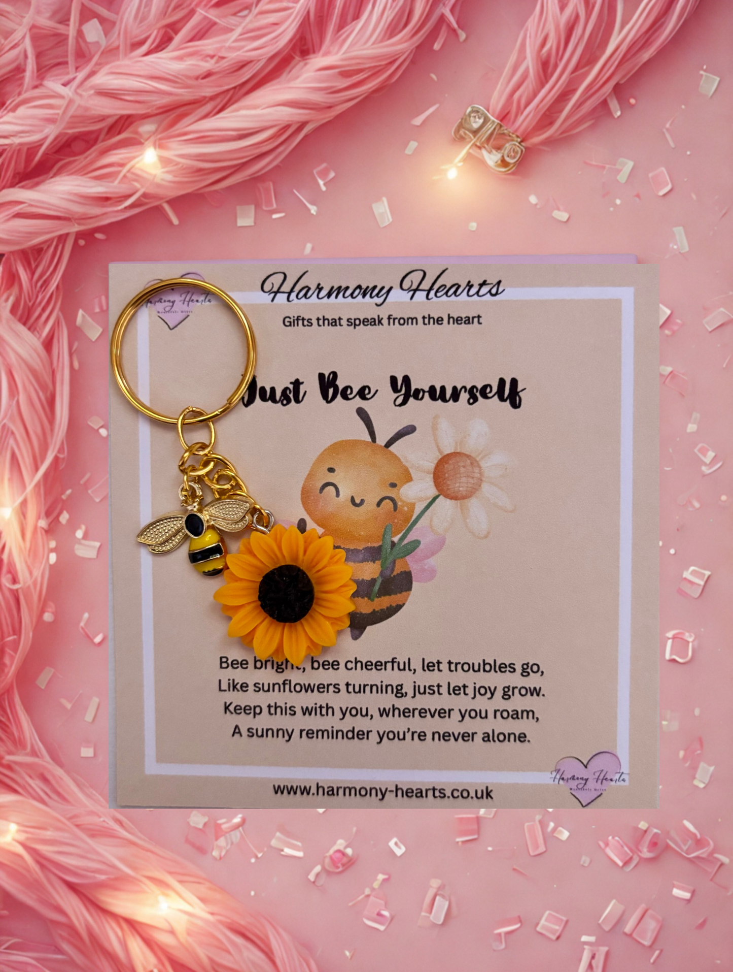Keychain with bee and sunflower design on a pink background with 'Harmony Hearts' branding.
