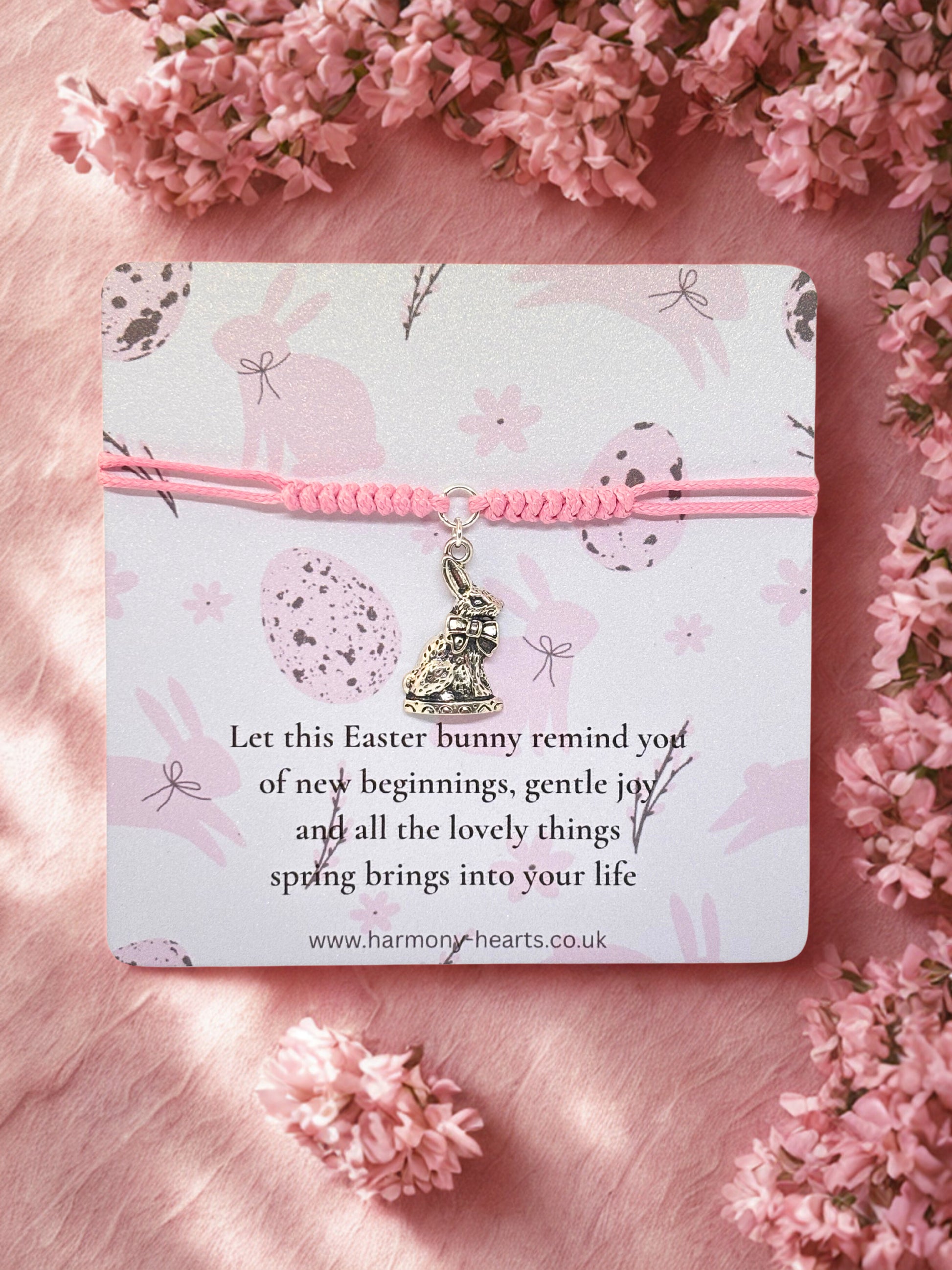 Pink bracelet with Easter bunny charm on a card surrounded by pink flowers