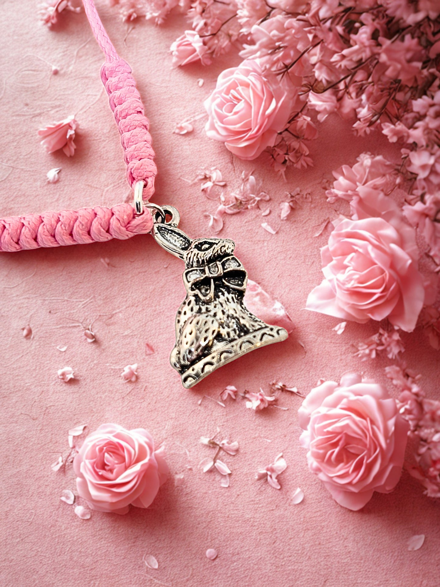 Pink bracelet with a bunny charm on a pink background with flowers