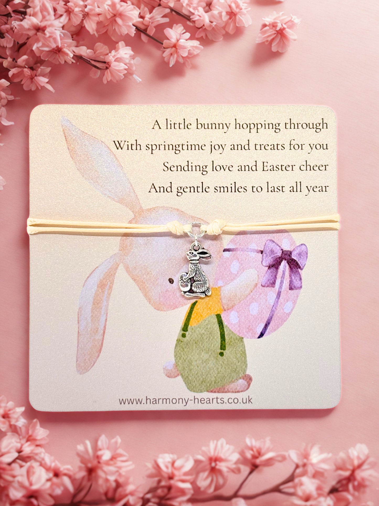 Easter themed card with a bunny design and and bunny charm bracelet on a cherry blossoms pink background