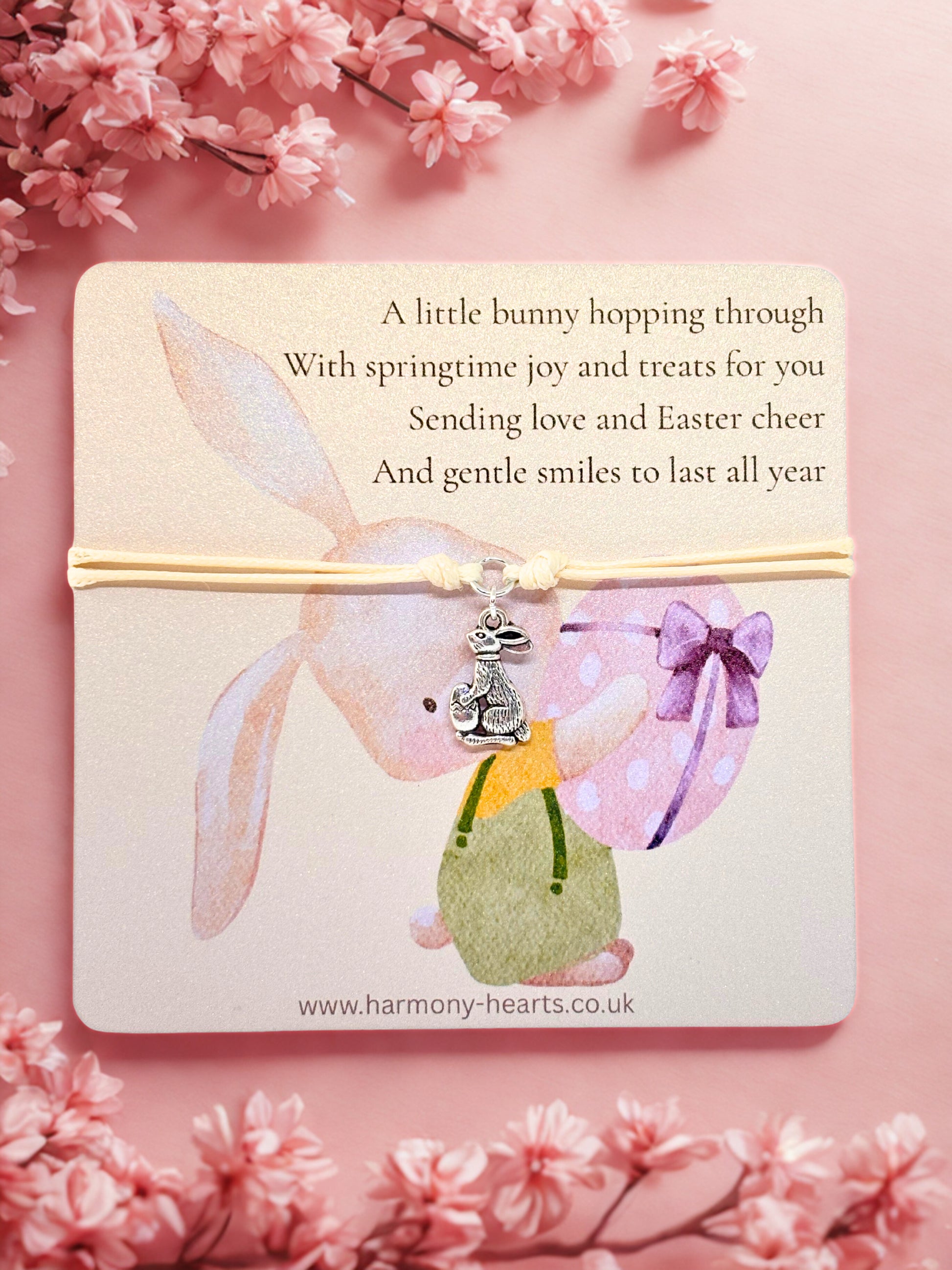 Easter themed card with a bunny design and and bunny charm bracelet on a cherry blossoms pink background
