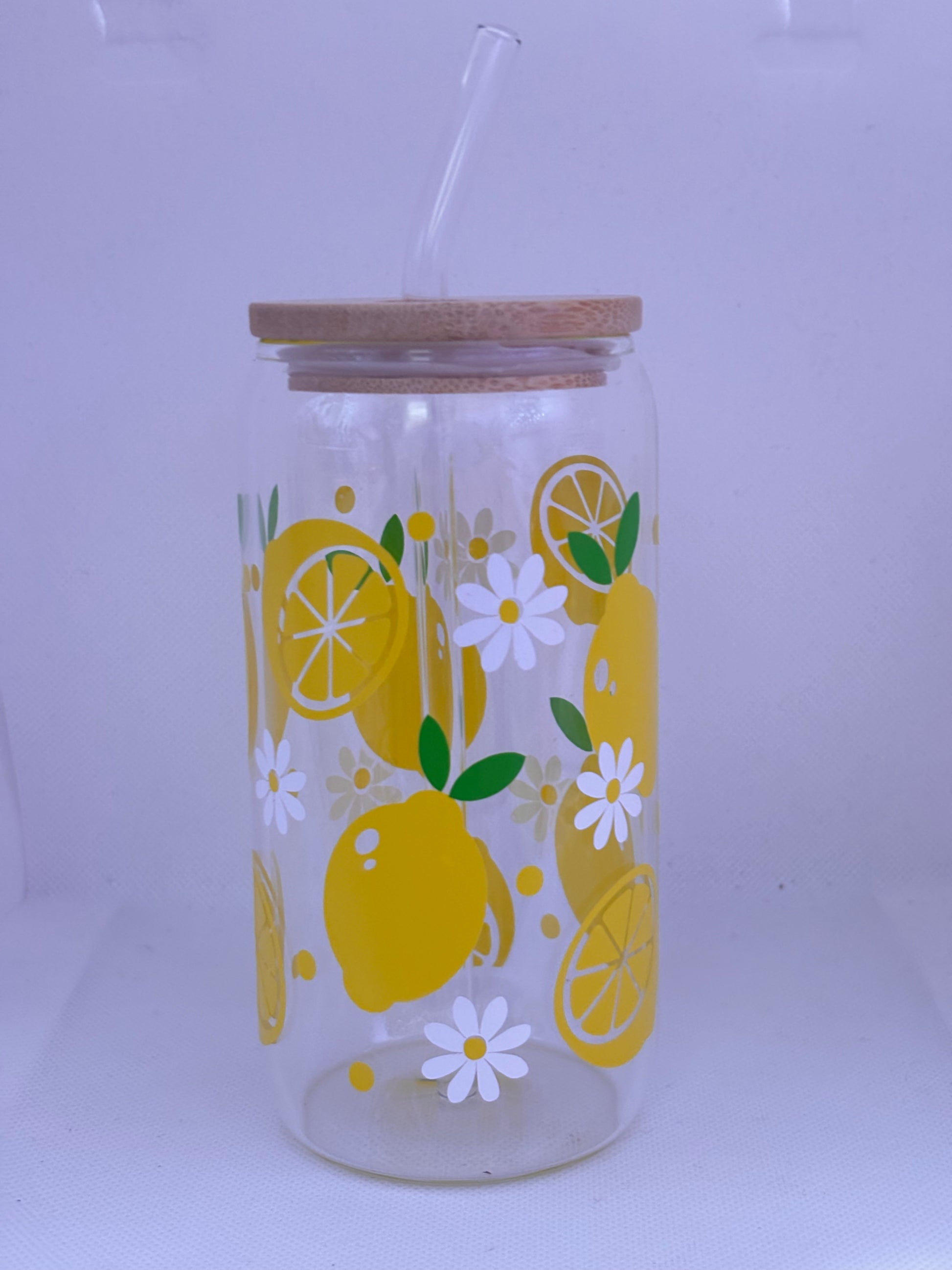 Clear glass tumbler with lemon and flower design and wooden lid on a white background