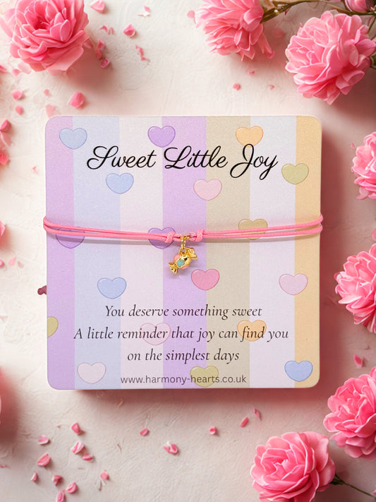 Pink cord bracelet with a gold and enamel sweet charm presented on a branded Harmony Hearts card
