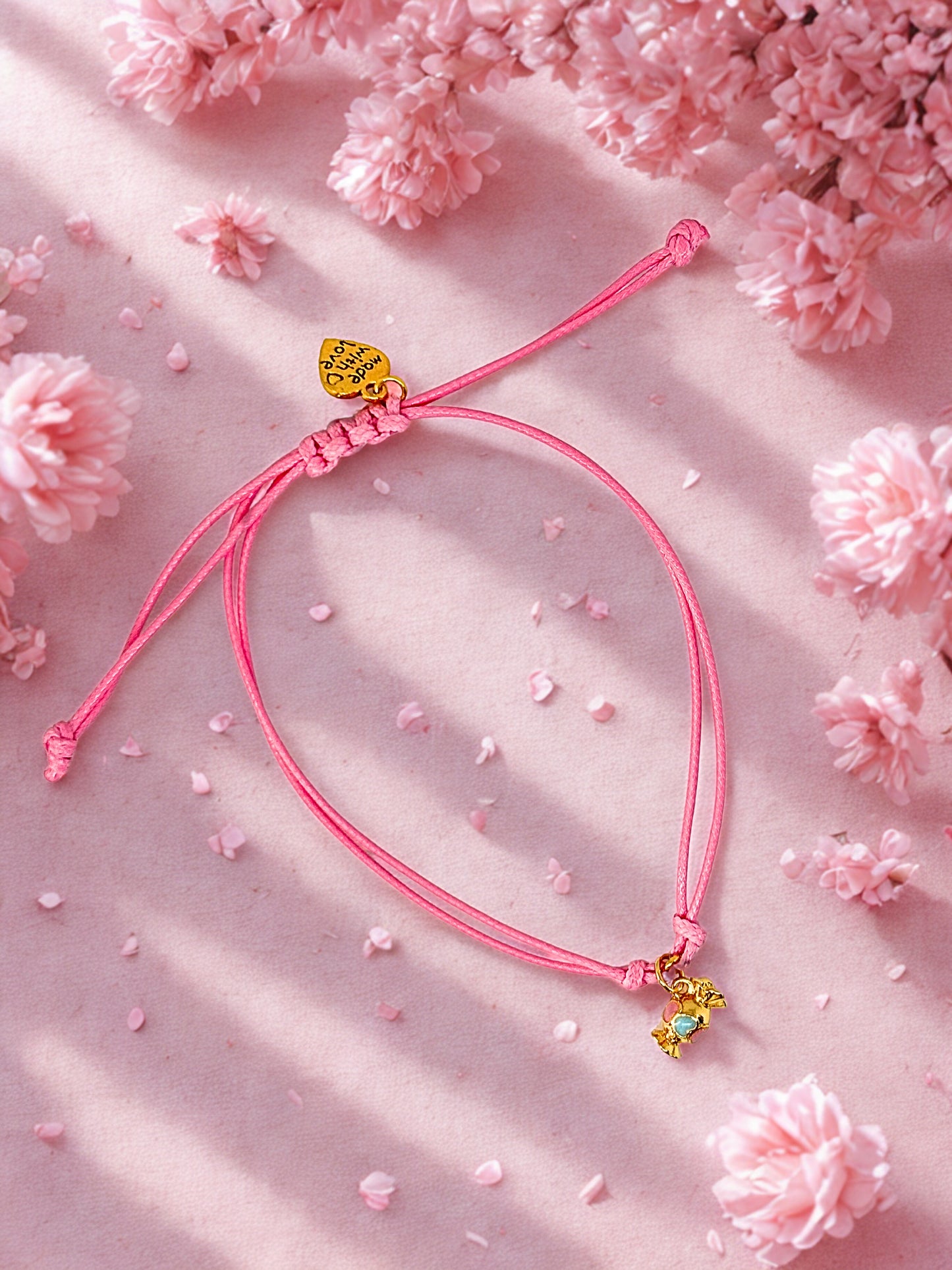Pink cord bracelet with a gold and enamel sweet charm