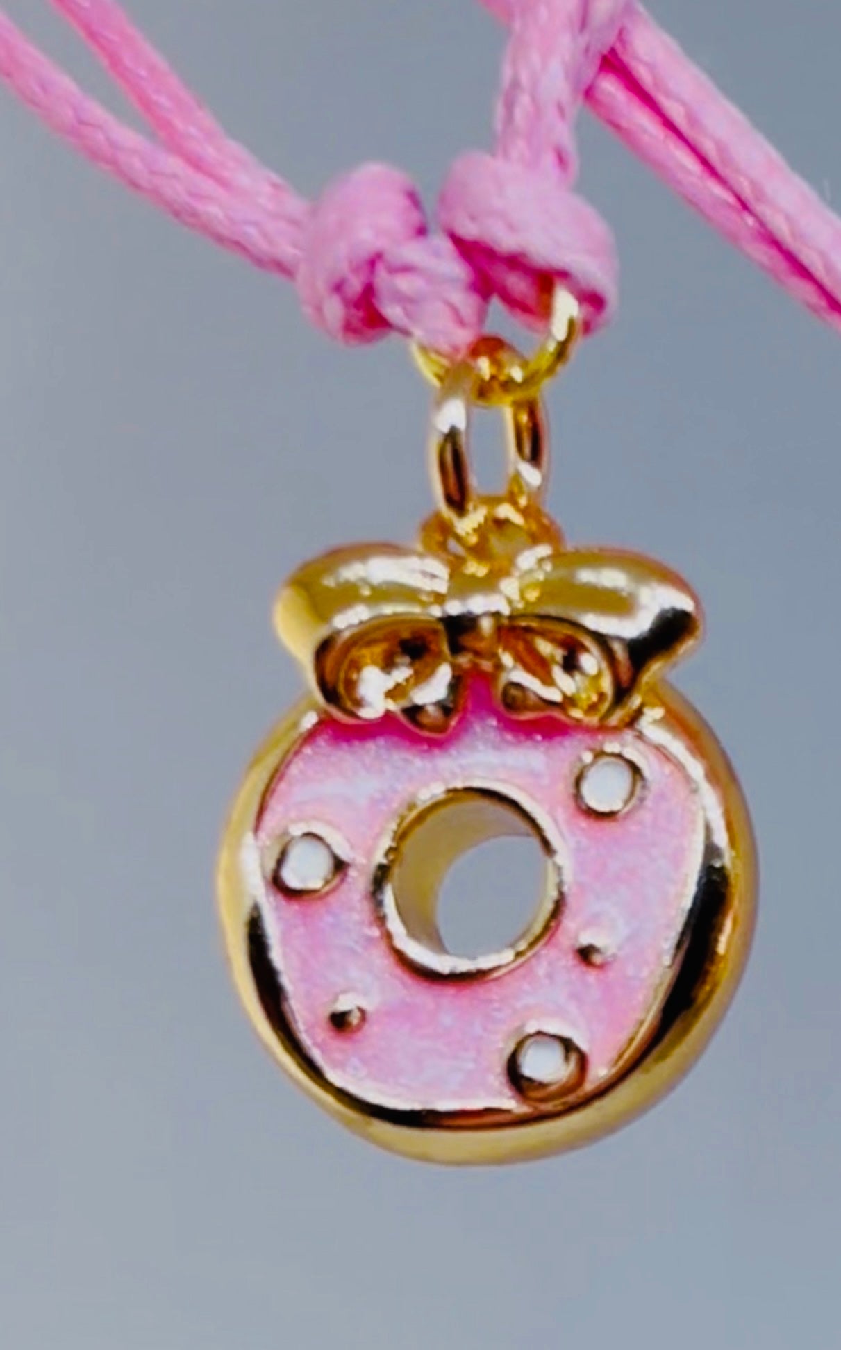 Pink and gold donut charm on a pink bracelet cord