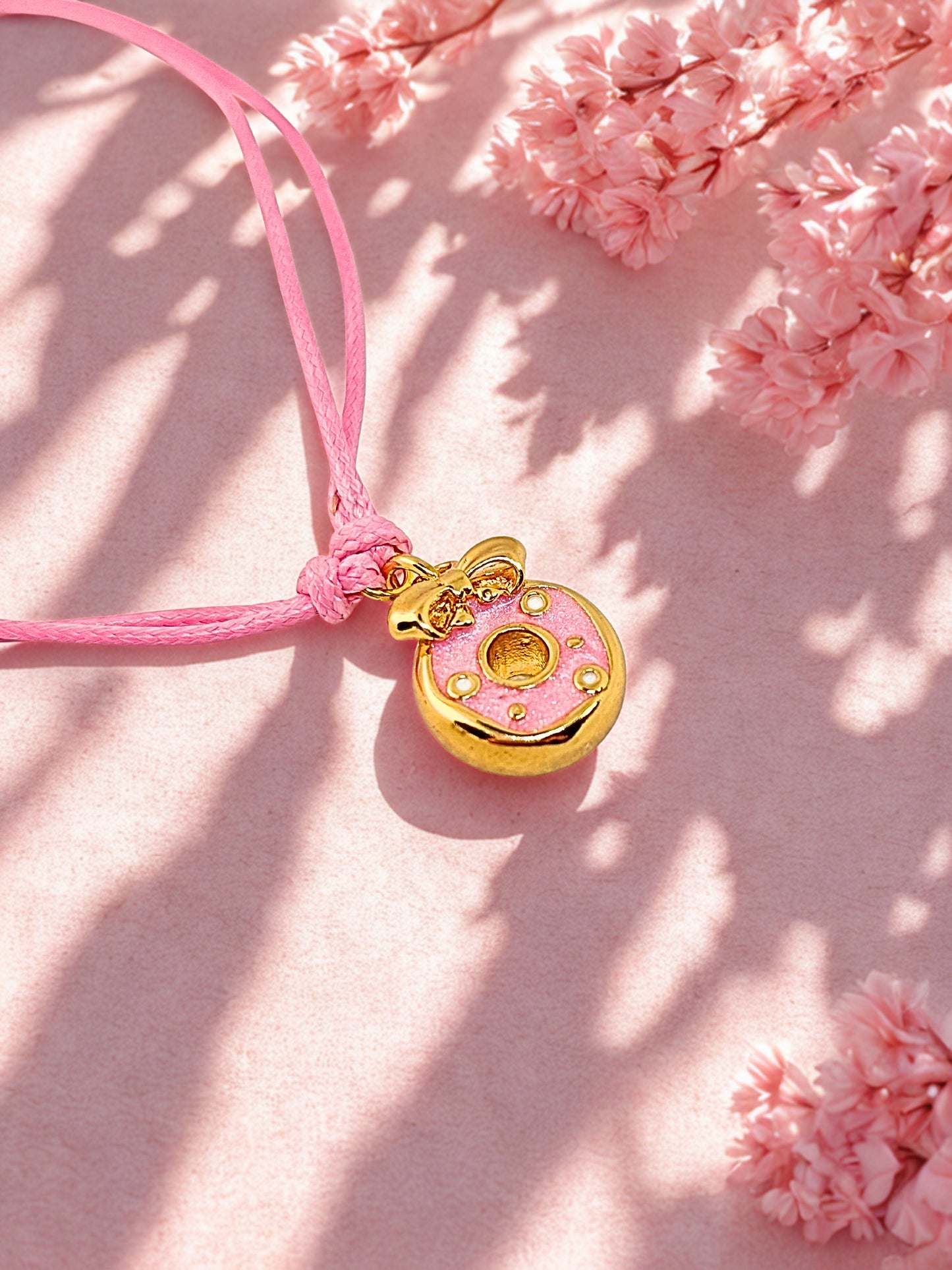 Pink and gold donut charm on a soft pink cord