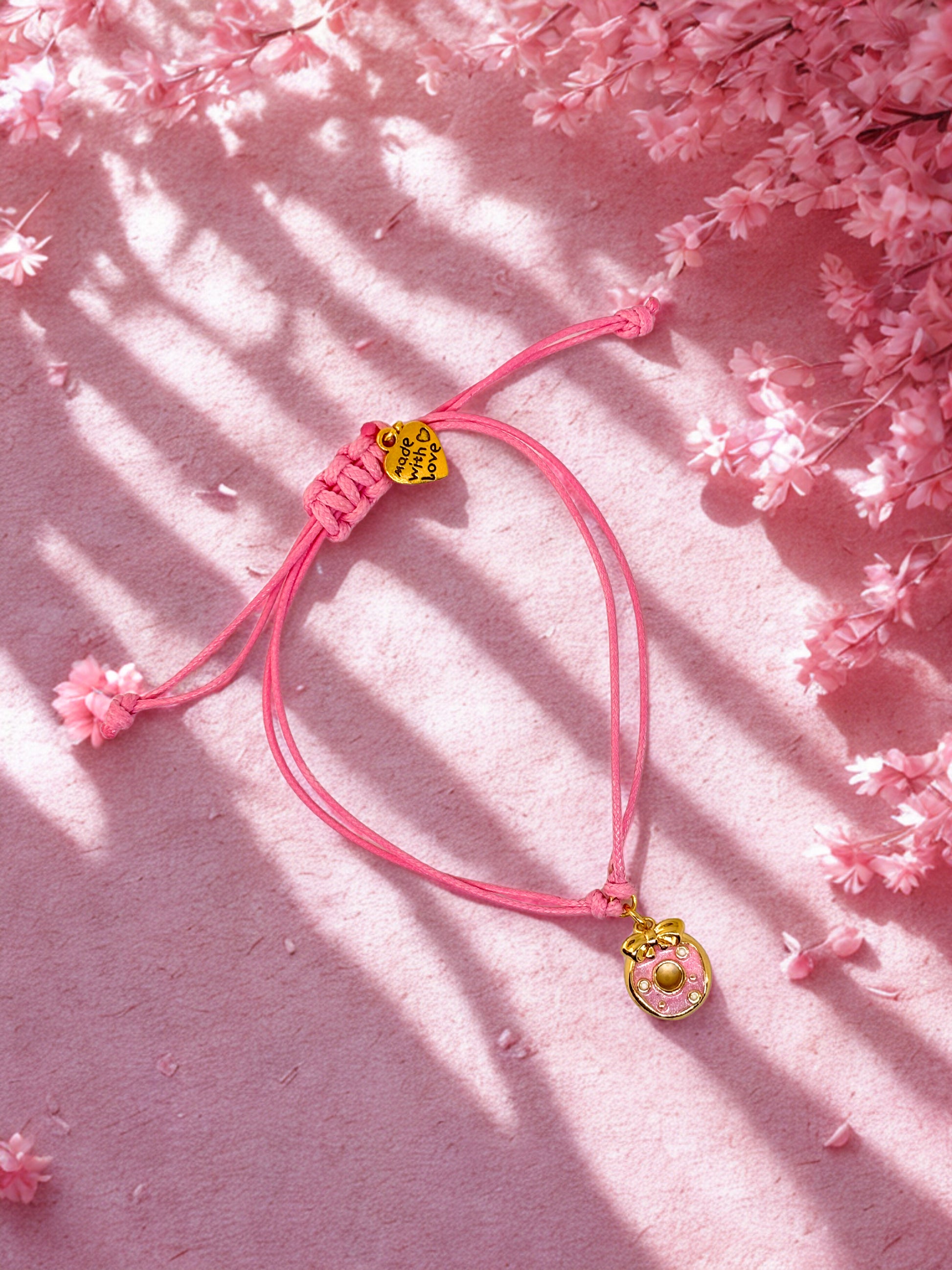 Pink cord charm bracelet with a pink and gold donut charm