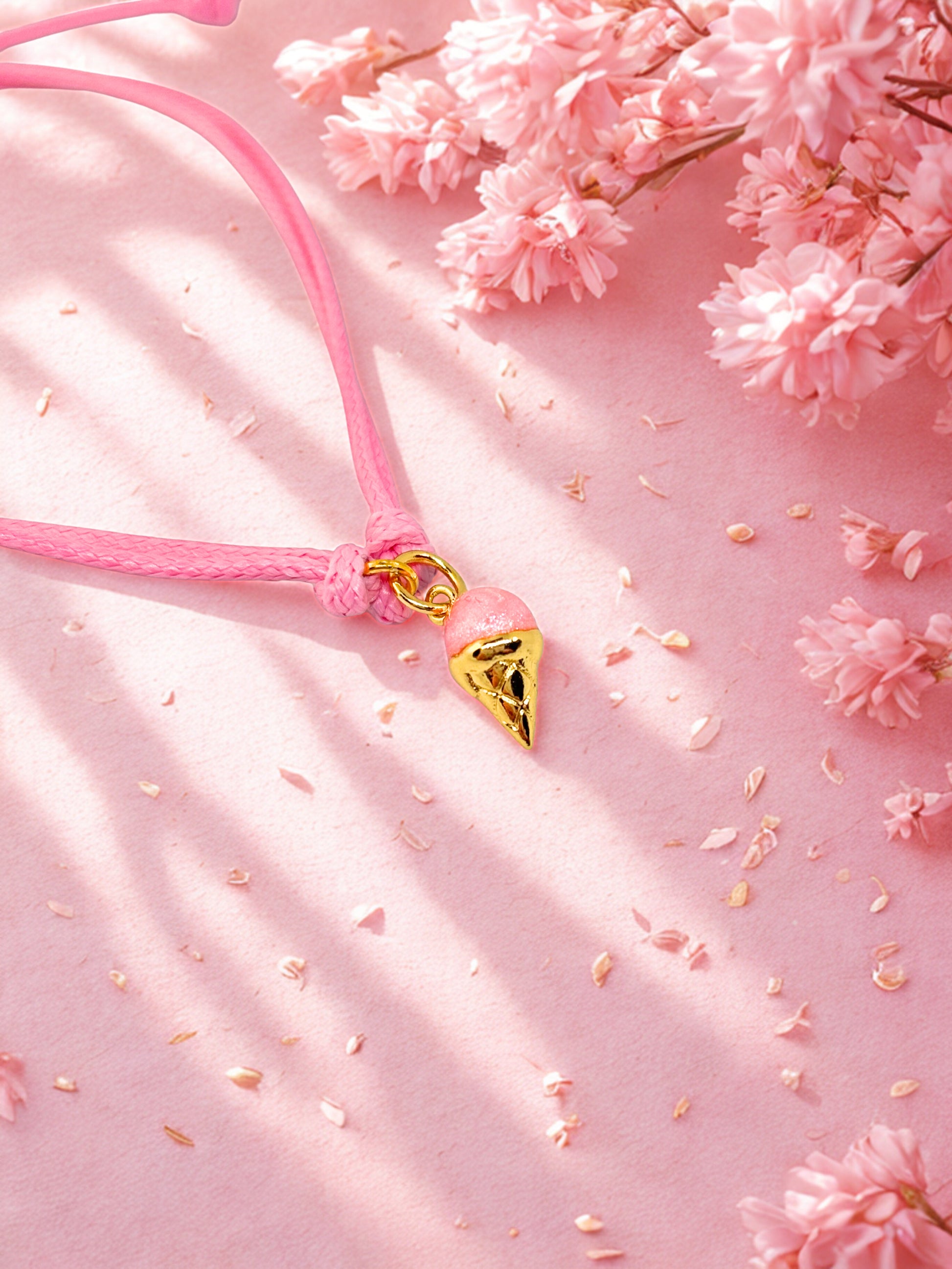 Pink cord bracelet with a pink and gold ice ream charm