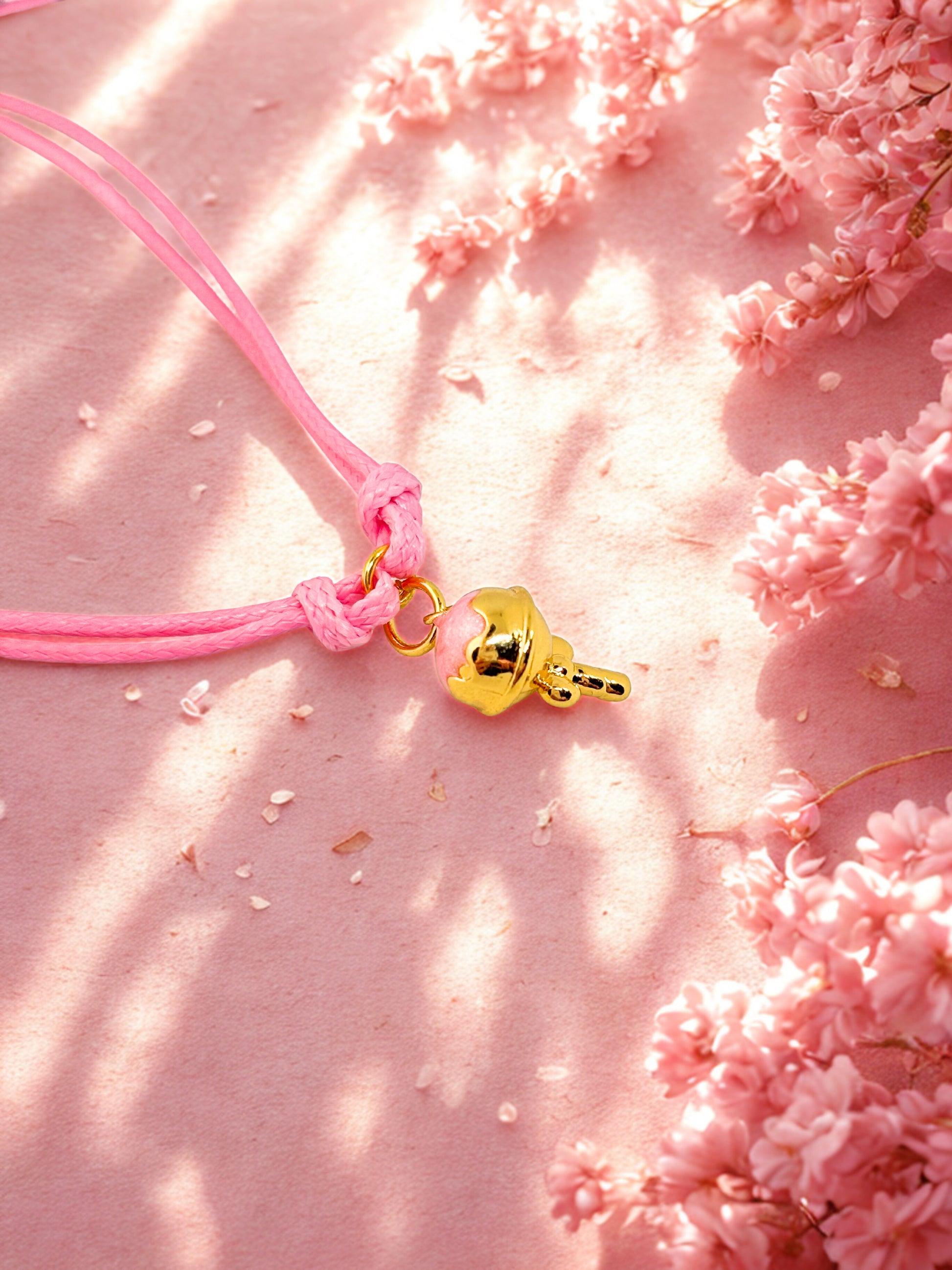 Pink cord charm bracelet with a pink and gold ice cream charm