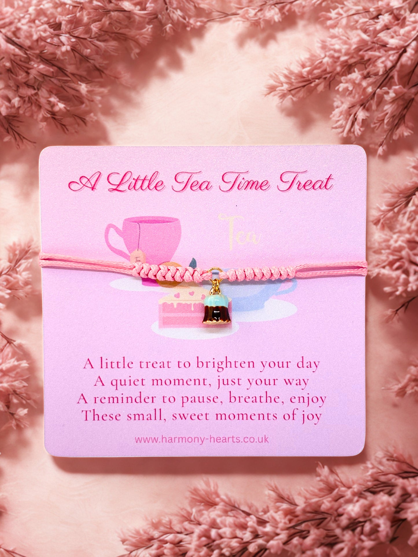 Pink cord bracelet with dessert charm presented on a Harmony Hearts branded card featuring a teacup charm on a pink floral background