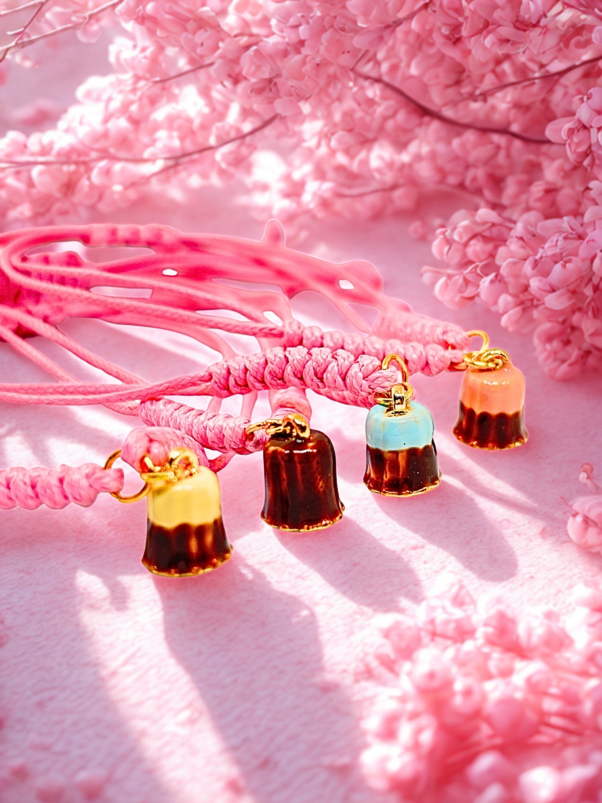 Pink braided cord bracelets with dessert inspired charms on a pink floral background