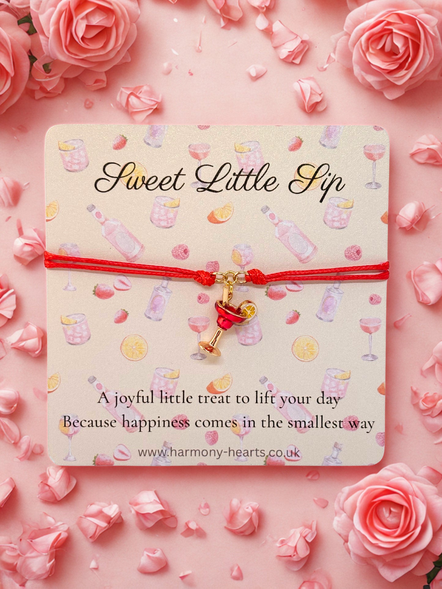 Cocktail charm bracelet on a card with 'Sweet Little Sip' text, surrounded by pink roses on a pink background