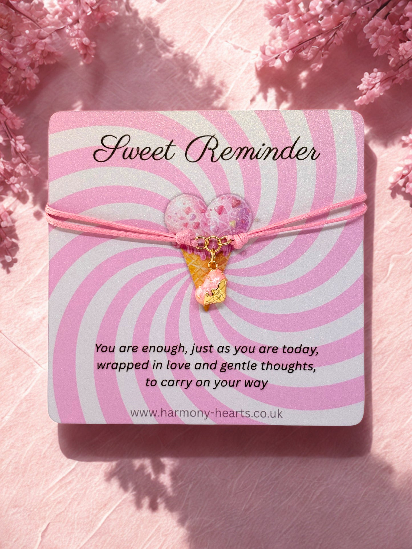 Pink and white striped card with a heart charm and motivational message on a pink floral background.