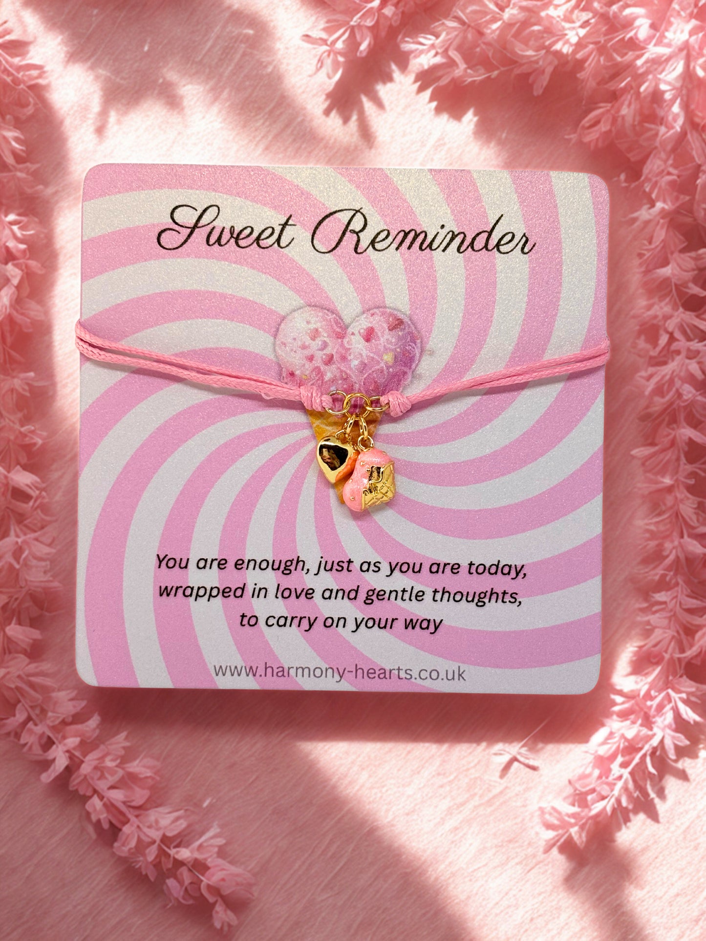 Pink bracelet with heart charm on a 'Sweet Reminder' card with text and website URL.