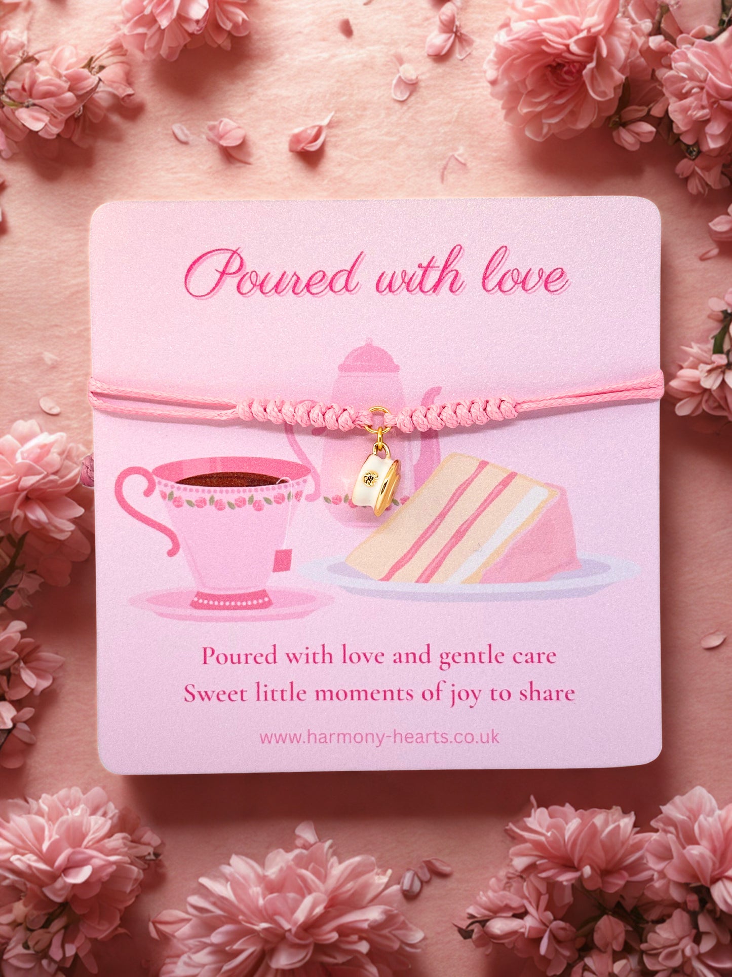 Pink bracelet with a teacup charm presented on a pink card with tea cup and cake illustration on a pink floral background