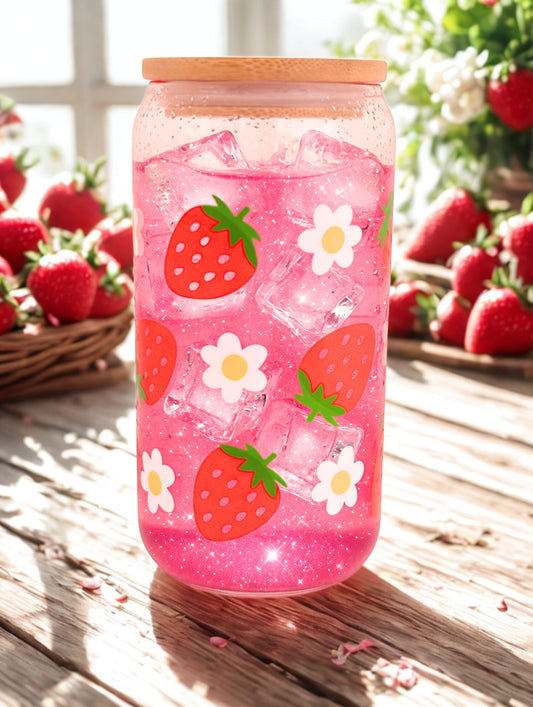 Glass tumbler with strawberry and flower design on a wooden surface with strawberries in the background