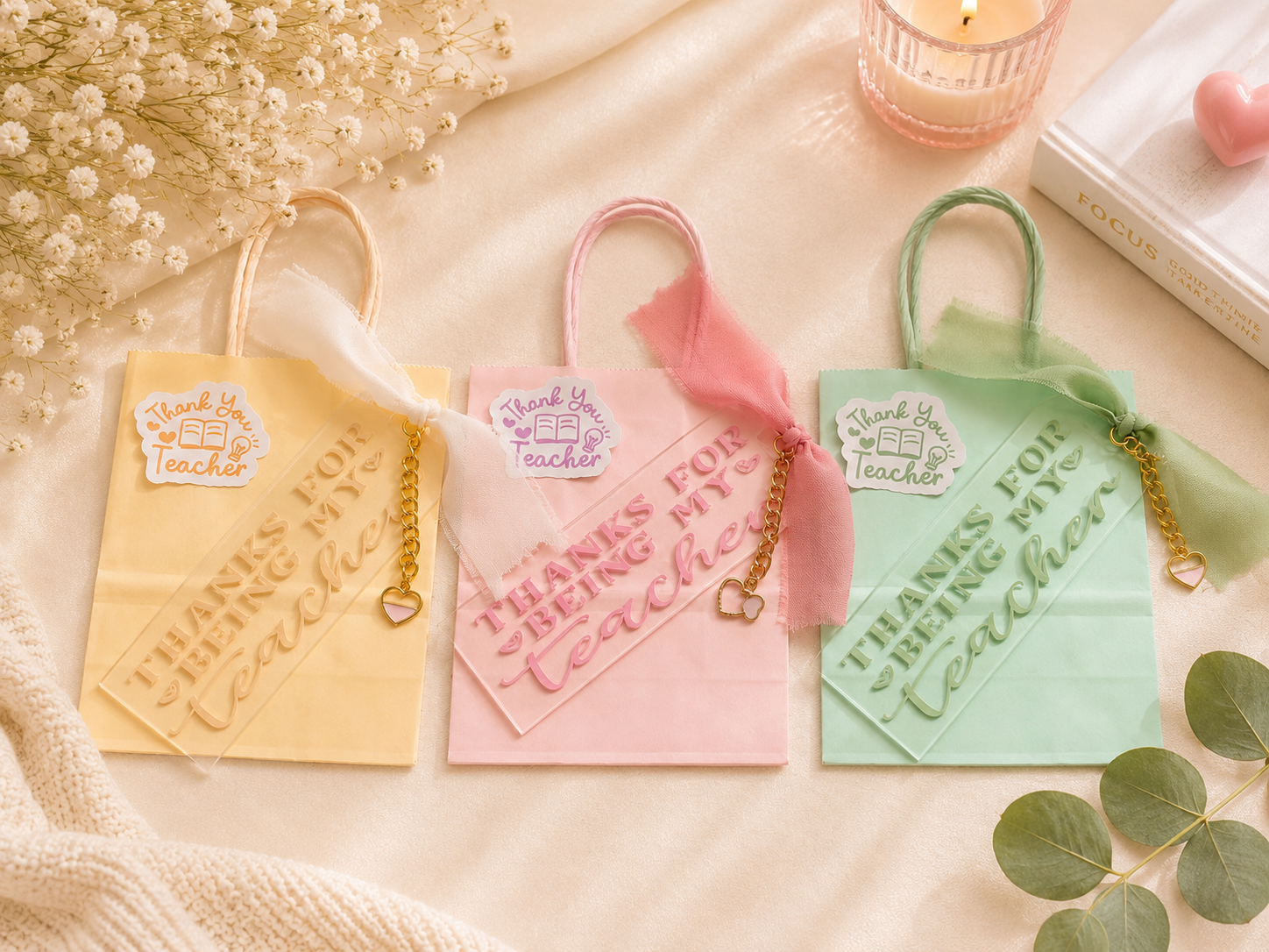 Three colorful bookmarks with 'Thanks for being my teacher' text on a soft surface with flowers and a candle.