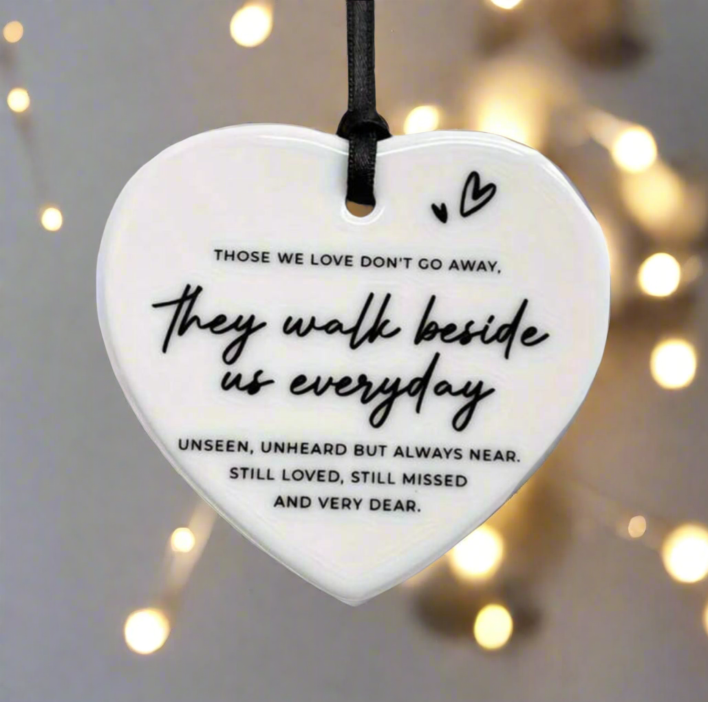 Heart-shaped  ornament with a quote on it, hanging against a blurred background with lights.