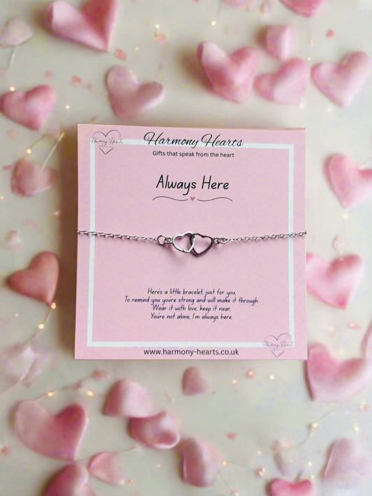 Heart-shaped bracelet on a pink card with 'Harmony Hearts' branding, surrounded by heart-shaped petals.

