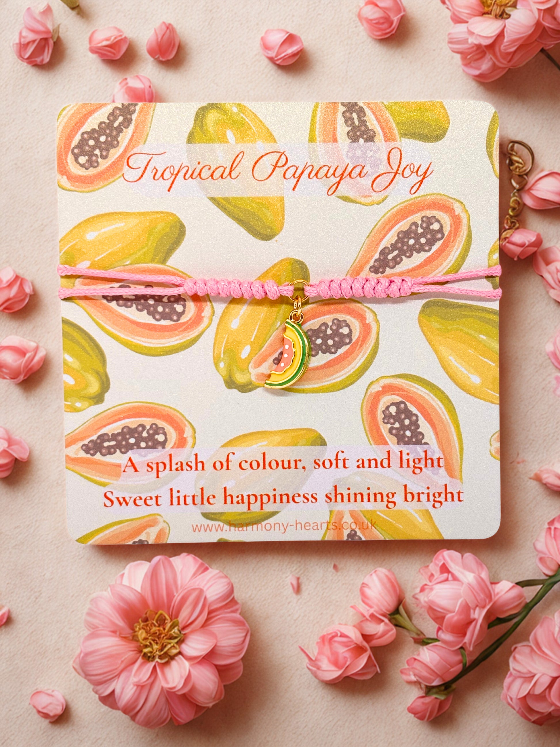 Pink cord bracelet with a papaya charm presented on a branded Harmony Hearts card