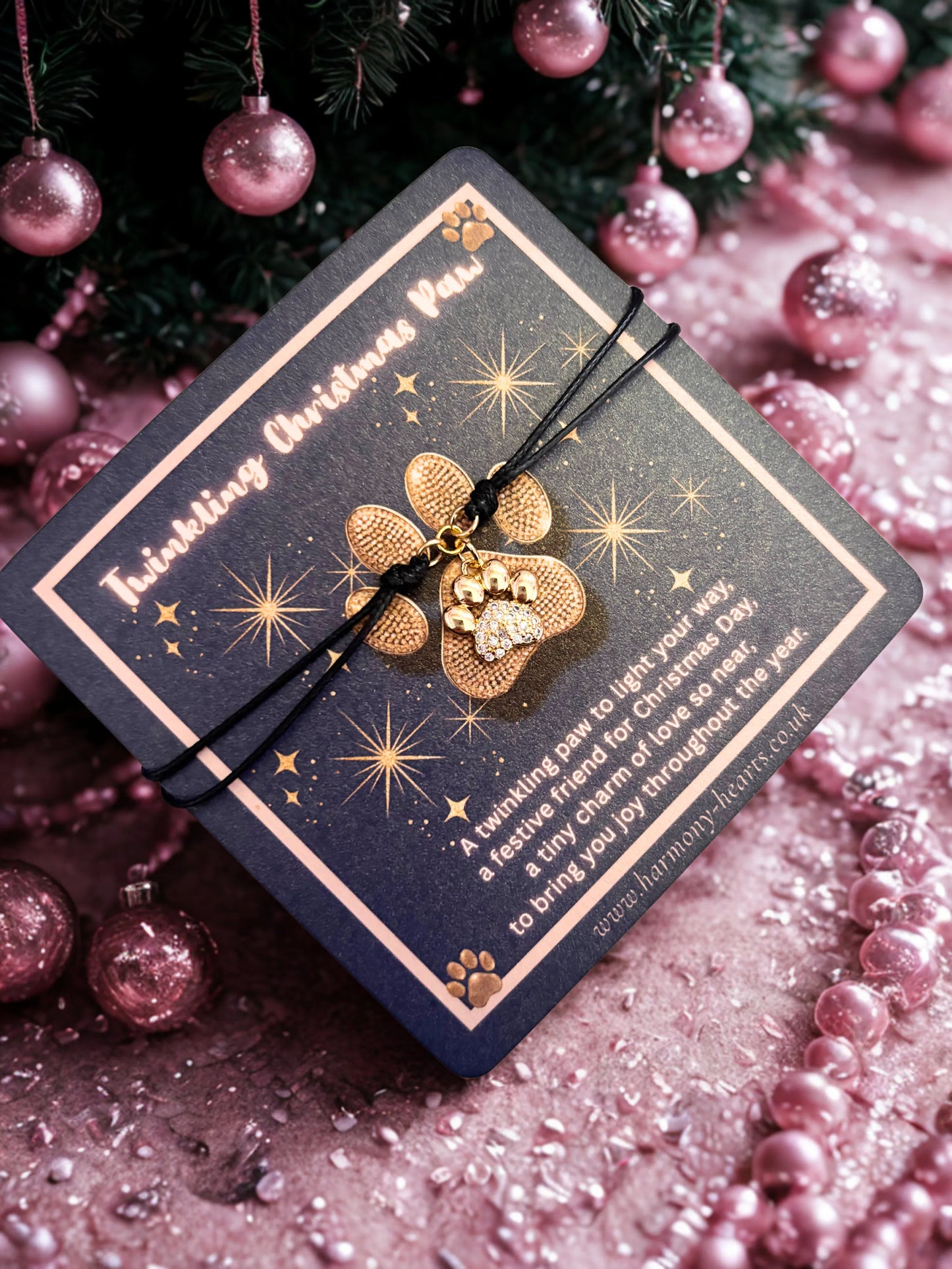 Gold paw-shaped charm on a black cord with a decorative card against a festive background.