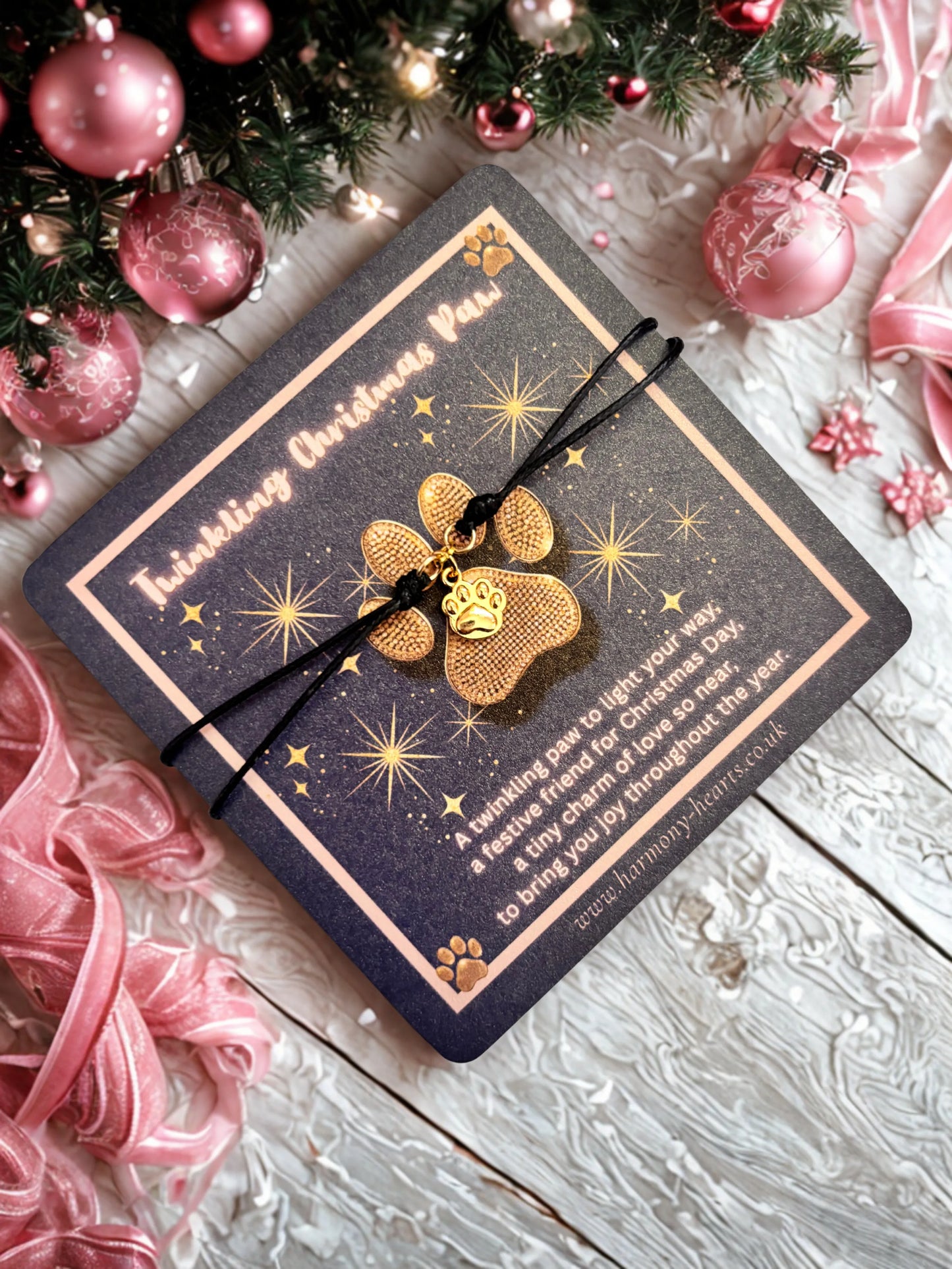 Gold paw charm on a card with Christmas decorations in the background