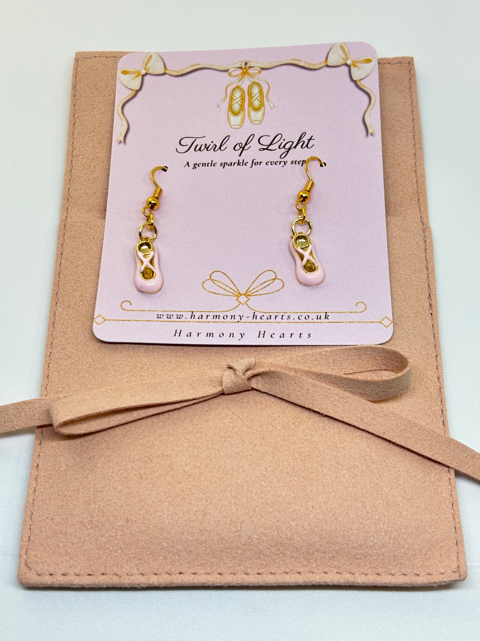 Pair of ballet slipper earrings on a 'Twist of Light' card with a beige ribbon.